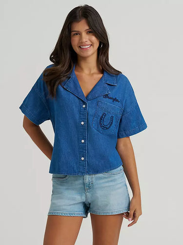 Cowboy Spirit Camp Shirt by Wrangler at 6Whiskey, six whisky, Women’s embroidered denim camp shirt, front pocket, embroidered, horseshoe, wrangler logo, bucking bronco rider on the back, front button closure, wide collar, flowy short sleeves, cropped length, soft, comfortable, lightweight, warm weather, spring, summer, casual western, modern, front view