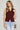 Woman wearing a maroon sleeveless knit vest with gold buttons and light-wash jeans, styled for Texas A&M game day and fall tailgates at 6whiskey six whisky