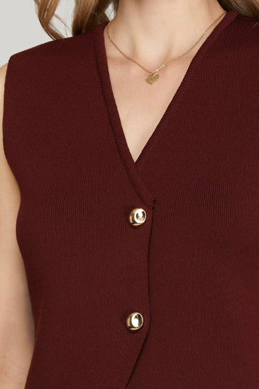 Close-up of a burgundy sleeveless top with gold buttons and a necklace.