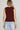 Woman wearing a maroon sleeveless knit vest with gold buttons and light-wash jeans, styled for Texas A&M game day and fall tailgates at 6whiskey six whisky