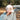 Prickly Pear Hat at 6Whiskey six whisky concho A man in a light blue long-sleeve shirt adjusts a cream-colored cap with red "CONCHO" lettering and an embroidered prickly pear cactus, standing outdoors with golden grass and oak trees in the background.