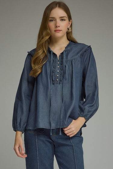 Denim darling blouse at 6whiskey, six whisky, woman wearing a blue denim blouse with jeans, ideal for fall game day or tailgate looks at texas a&m, aggies, SEC, gameday outift inspo, ruffle detail blouse with buttons and self tie, elasticated gathered long sleeve blouse, front view, football game outfit, watch party look, game day to weekday look. Pair with maroon or burgundy accessories and sneakers, sandals, or boots. Texas A&M casual chic aggie style.