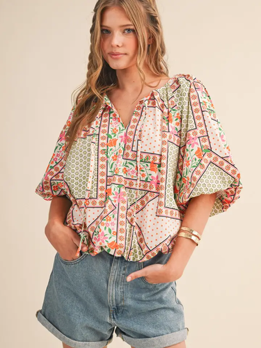 Maribel Mosaic Blouse at 6Whiskey, six whisky, split neckline, v-neckline, tie tassel front, 1/2 sleeve, flutter sleeve, puff sleeve, short sleeve, floral patterned, panel, geometric, multicolor, green, pink, orange, cream, lightweight, flowy, relaxed, spring and summer, lunch, brunch, church, work to weekend, feminine, front view
