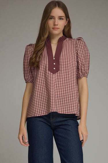 Gridiron gingham blouse at 6whiskey, six whisky, woman wearing a burgundy maroon gingham print blouse with jeans, ideal for fall game day or tailgate looks at texas a&m, aggies, SEC, gameday outift inspo, ruffle detail blouse, elasticated gathered mid length sleeve blouse, front view, football game outfit, watch party look, game day to everyday look. Pair with black, white, or blue jean denim or aggie accessories and sneakers, sandals, or boots. Texas A&M aggie style. Casual chic aggie style.