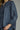 Denim darling blouse at 6whiskey, six whisky, woman wearing a blue denim blouse with jeans, ideal for fall game day or tailgate looks at texas a&m, aggies, SEC, gameday outift inspo, ruffle detail blouse, elasticated gathered long sleeve blouse, up close front detail view, football game outfit, watch party look, game day to weekday look. Pair with maroon or burgundy accessories and sneakers, sandals, or boots. Texas A&M aggie style. Casual chic aggie style. Button up front and self tie detail.