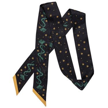 a luxurious, hand-illustrated 100% silk twilly scarf with a midnight black background, adorned with golden stars and deep teal swirling lasso motifs. The design embodies a celestial Western theme, symbolizing adventure and limitless possibilities. With gold-accented edges and a sleek, elongated shape (1.5" x 55"), this versatile accessory can be styled as a necktie, headband, or bag accent, adding a touch of cosmic cowgirl charm to any outfit