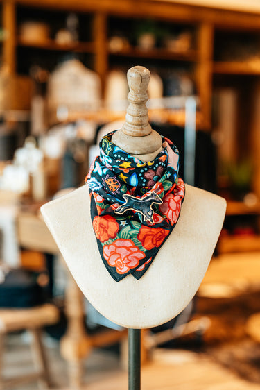Rose Ranch Bandana by XOXO Art at 6Whiskey, six whisky, square, silk cotton bled, Mexican roses, western designs, hand drawn, sketch, modern, cool girl, edgy western, casual, stylish, colorful, pop of color, unique, black base, reds and pinks, tied view. 