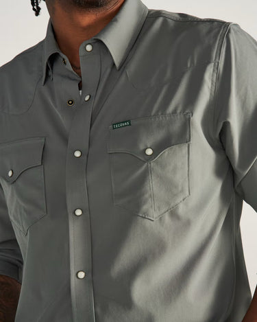 Long Sleeve Performance Pearl Snap in cactus green by Tecovas at 6Whiskey, six whisky, green pearl snaps, brass rings, stretch, comfortable, breathable, texas weather, SEC, southern charm, western stitching, front pockets, lightweight, men's must have, men's gift idea, rodeo, country concert, date night, work, elevated western, sweat proof, ventilated, collared, front view. hidden sunglass wipe, hidden sunglass pocket. sleeve rolled up or down up close detail of pockets and snaps