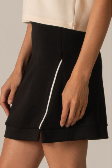 Piping Black Mini Skirt by P.cill at 6Whiskey, six whiskey, white side piping, high elastic waistband, comfy, cozy, sporty, elevated, classy, chic, sleek, matching set, pickleball, errands, loungewear. Side view.