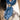 Person wearing a blue bandana with white patterns and a gold buckle, over a white shirt with a horse design at 6Whiskey six whisky fringe scarves western accessory