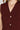 Close-up of a burgundy sleeveless top with gold buttons and a necklace.