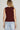 Woman wearing a maroon sleeveless knit vest with gold buttons and light-wash jeans, styled for Texas A&M game day and fall tailgates at 6whiskey six whisky