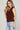 Woman wearing a maroon sleeveless knit vest with gold buttons and light-wash jeans, styled for Texas A&M game day and fall tailgates at 6whiskey six whisky