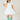 6Whiskey six whisky Woman wearing a short white lace western dress with puff sleeves and tiered skirt, styled with turquoise cowboy boots—perfect for bridal showers, country concerts, or summer events in Texas.