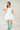 6Whiskey six whisky Woman wearing a short white lace western dress with puff sleeves and tiered skirt, styled with turquoise cowboy boots—perfect for bridal showers, country concerts, or summer events in Texas.