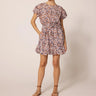Aurora Mini Dress at 6Whiskey six whisky Cleobella. A woman wearing a short, flutter-sleeve mini dress with a high neckline, removable waist sash, and an allover floral print in earthy tones; the dress features a ruffled hem and side pockets, styled with brown ankle-strap sandals.