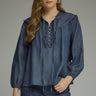 Denim darling blouse at 6whiskey, six whisky, woman wearing a blue denim blouse with jeans, ideal for fall game day or tailgate looks at texas a&m, aggies, SEC, gameday outift inspo, ruffle detail blouse with buttons and self tie, elasticated gathered long sleeve blouse, front view, football game outfit, watch party look, game day to weekday look. Pair with maroon or burgundy accessories and sneakers, sandals, or boots. Texas A&M casual chic aggie style.