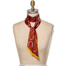 "Horseshoe Twilly" – a hand-illustrated, 100% silk twilly scarf in a rich maroon hue, featuring golden horseshoes, equestrian ribbon details, and the mantra "Giddy Up." Styled on a dress form, the scarf showcases its versatile design, perfect for wearing as a necktie, hair accessory, or bag accent. Finished with golden-yellow edges for a bold contrast.
