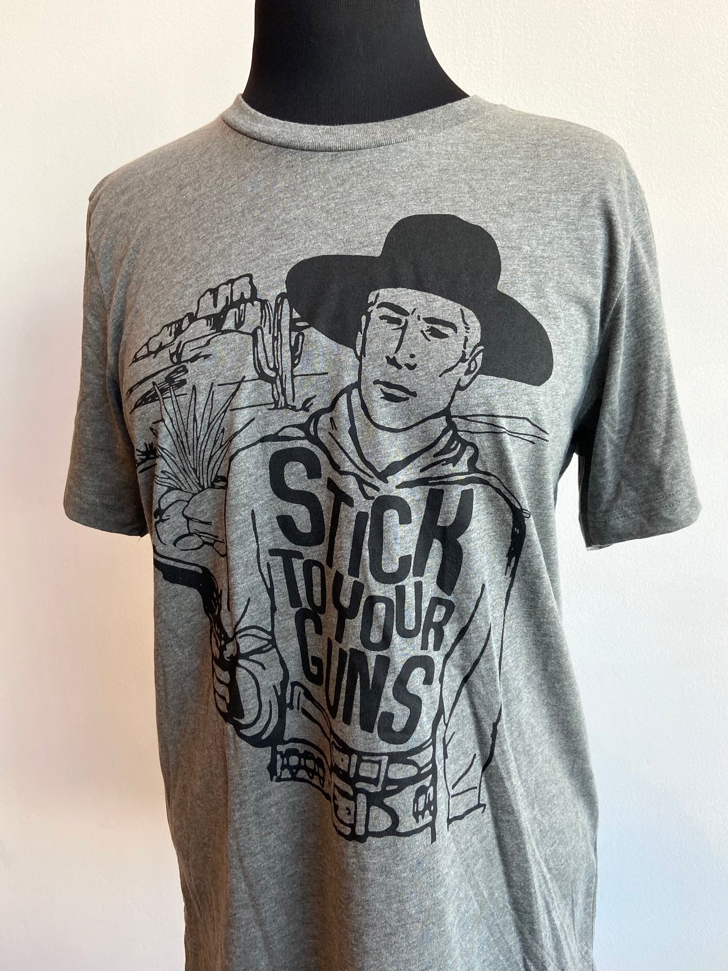 Grey graphic tshirt with black letters and cowboy saying stick to your guns short sleeve at 6Whiskey six whisky mens or womens bella canvas soft tee